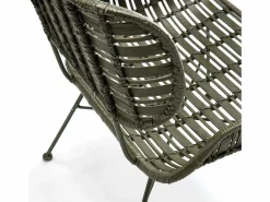 Les Tendances Sillón de mimbre tejido oscuro y patas de metal.